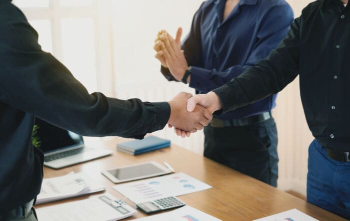 Businessman stand handshake and clapping of appreciation about the success of business at meeting.