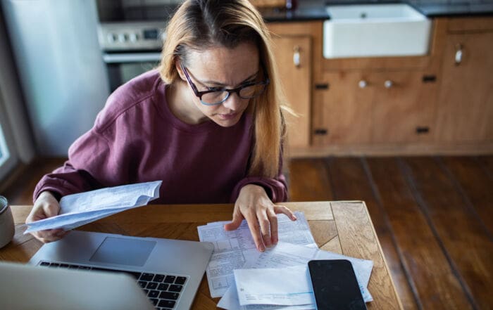 Woman reviewing household bills at home kitchen table